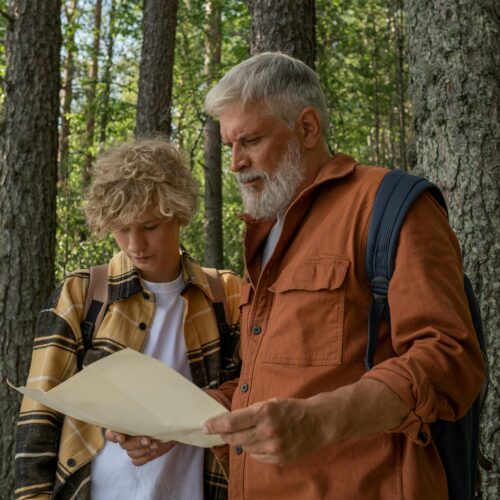 Grandfather and Grandson with Map during Hiking through Forest