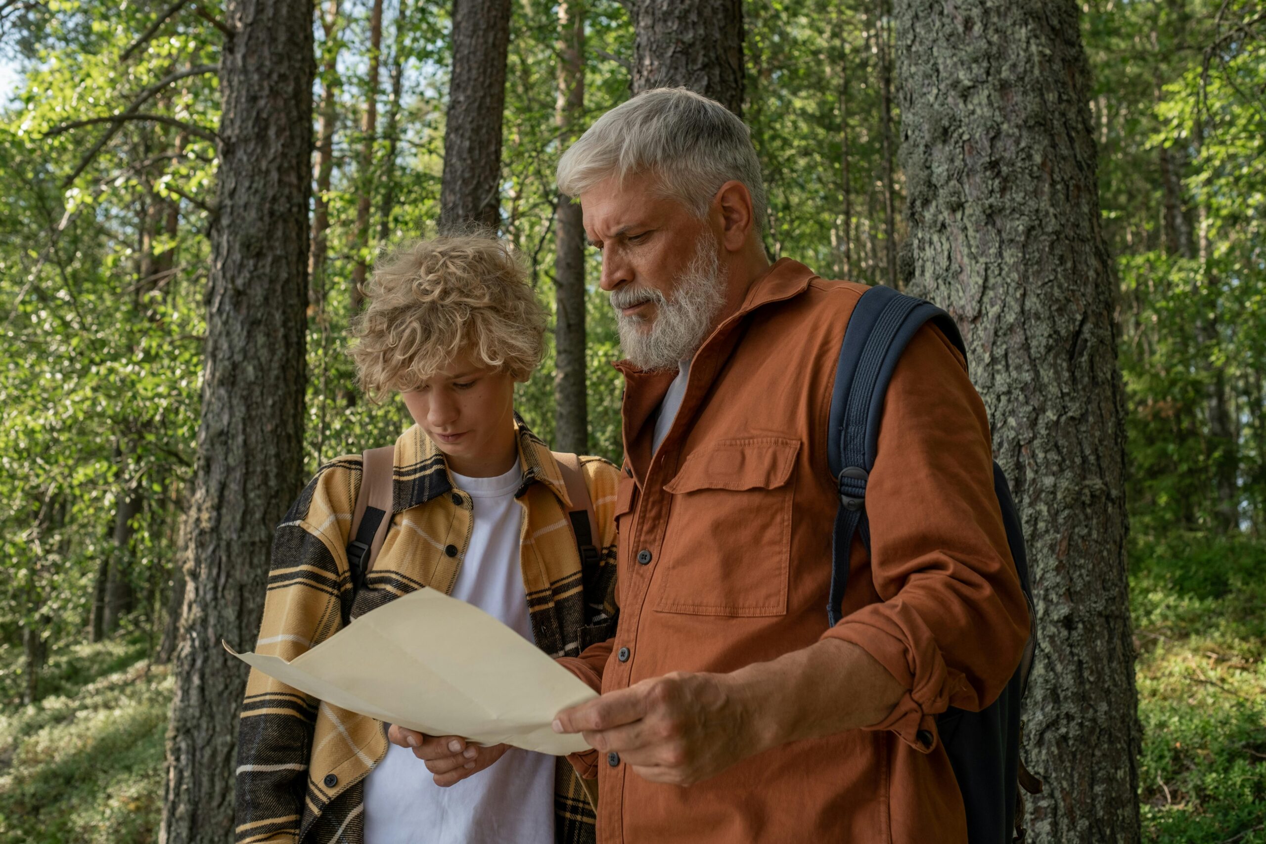 Grandfather and Grandson with Map during Hiking through Forest