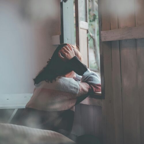 Photo of a Person Leaning on Wooden Window