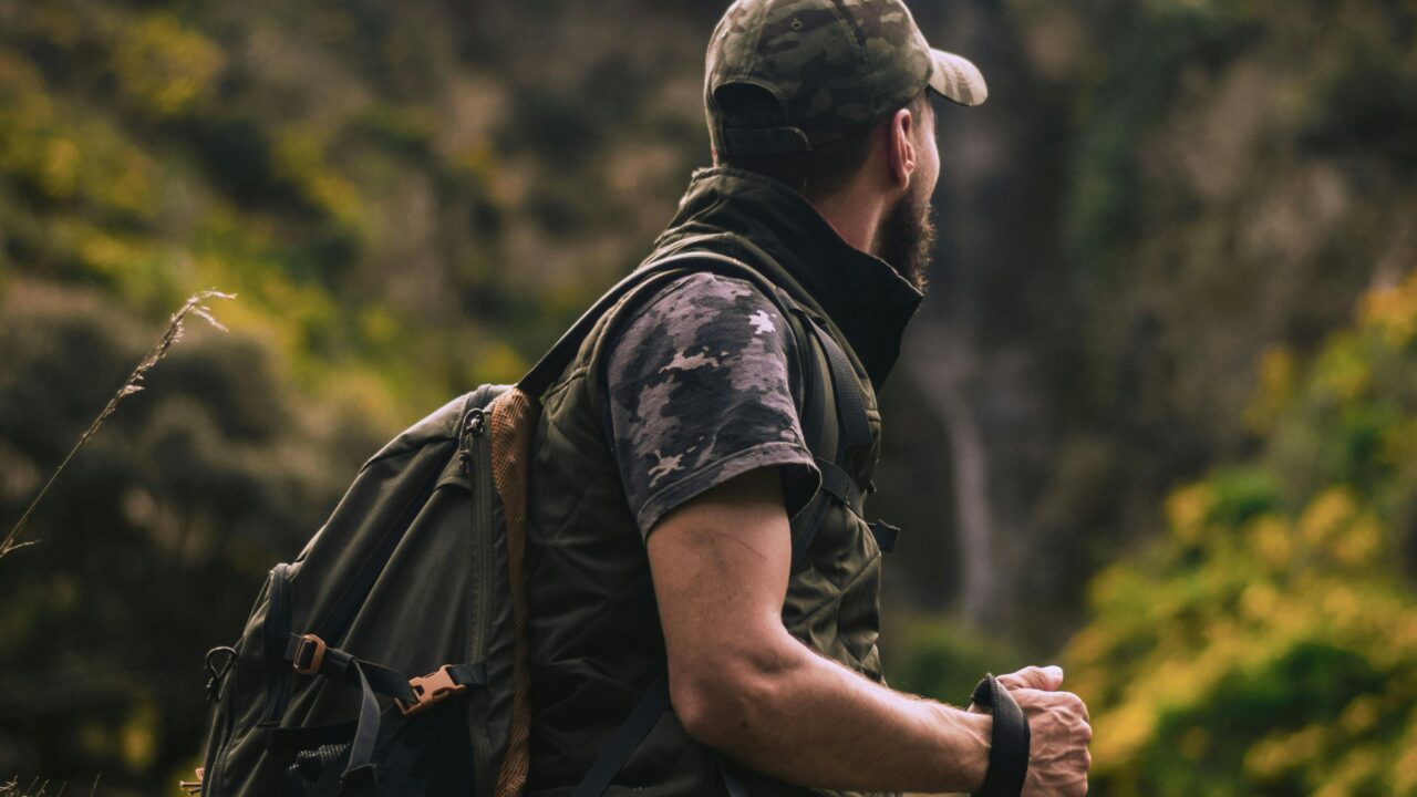 Man Wearing Cap and Crew-neck Shirt Standing in the Middle of Forest