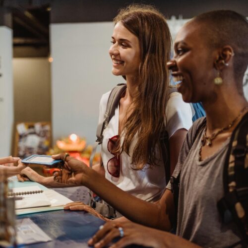 Women Receiving a Hotel Room Card at the Reception Desk 