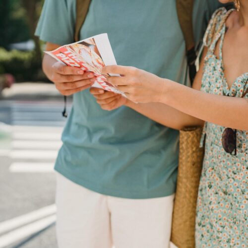 Crop anonymous couple searching direction in map while sightseeing together in city center during trip