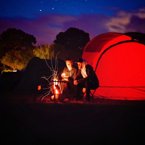 Man and Woman Sitting Beside Bonfire during Nigh Time