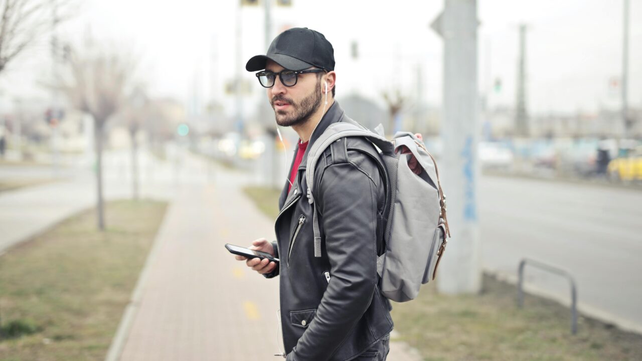 Man Wearing Black Leather Jacket Holding Smartphone