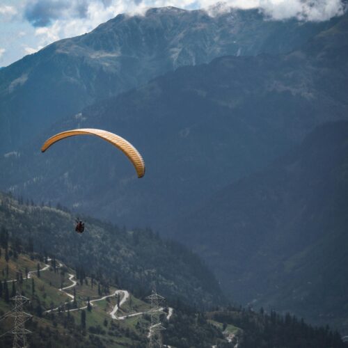 Person Riding Yellow Parachute over Mountain Range