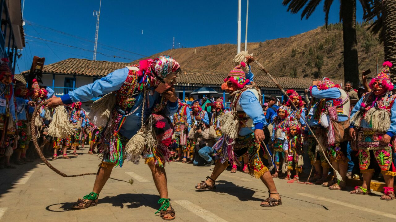 Colorful Andean festival featuring traditional costumes and ceremonial masks outdoors.