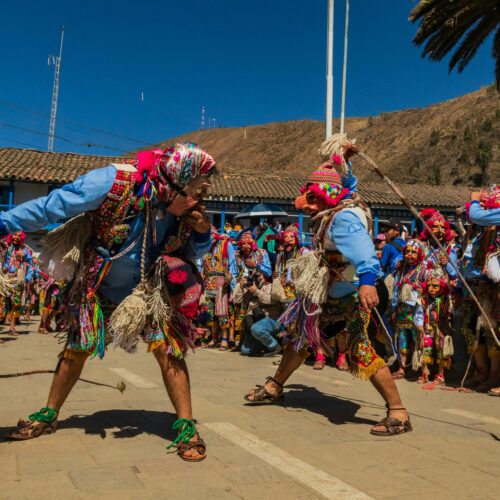 Colorful Andean festival featuring traditional costumes and ceremonial masks outdoors.