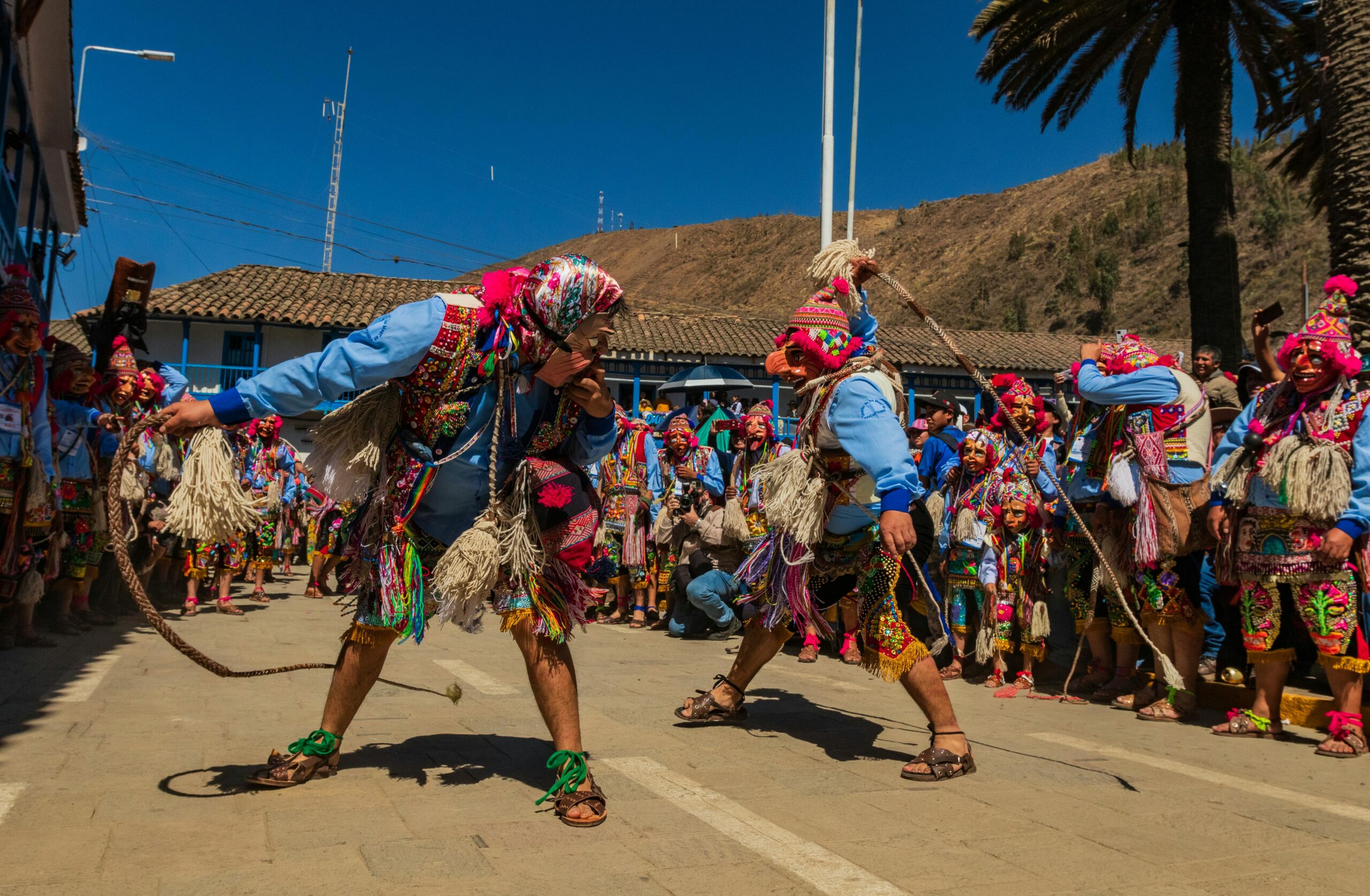 Colorful Andean festival featuring traditional costumes and ceremonial masks outdoors.